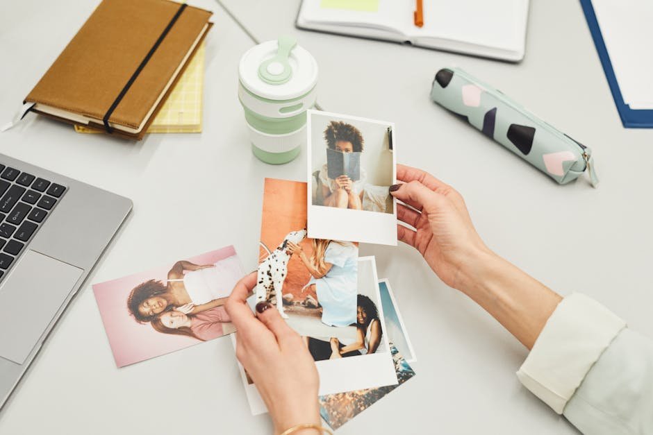 Close-up of hands holding polaroid photos on a creative workspace desk.