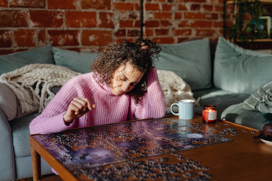 A woman enjoys assembling a jigsaw puzzle in a cozy, sunlit living room.