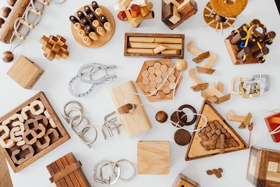 Top view of various wooden brain teaser puzzles on a white table, showcasing unique designs and playful challenges.