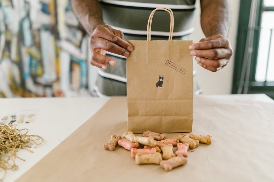 Hands pack colorful dog treats in a thank you kraft paper bag.